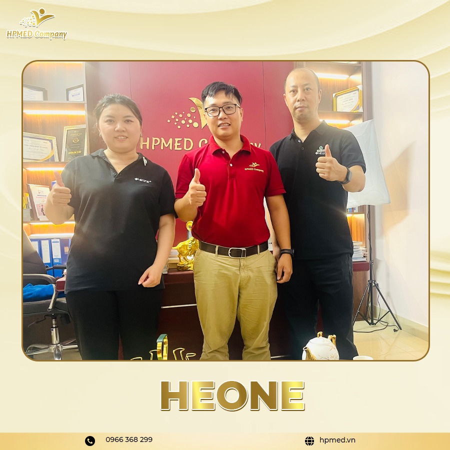 Ba nhân viên HPMED Company mặc đồng phục đứng trong văn phòng giơ ngón tay cái