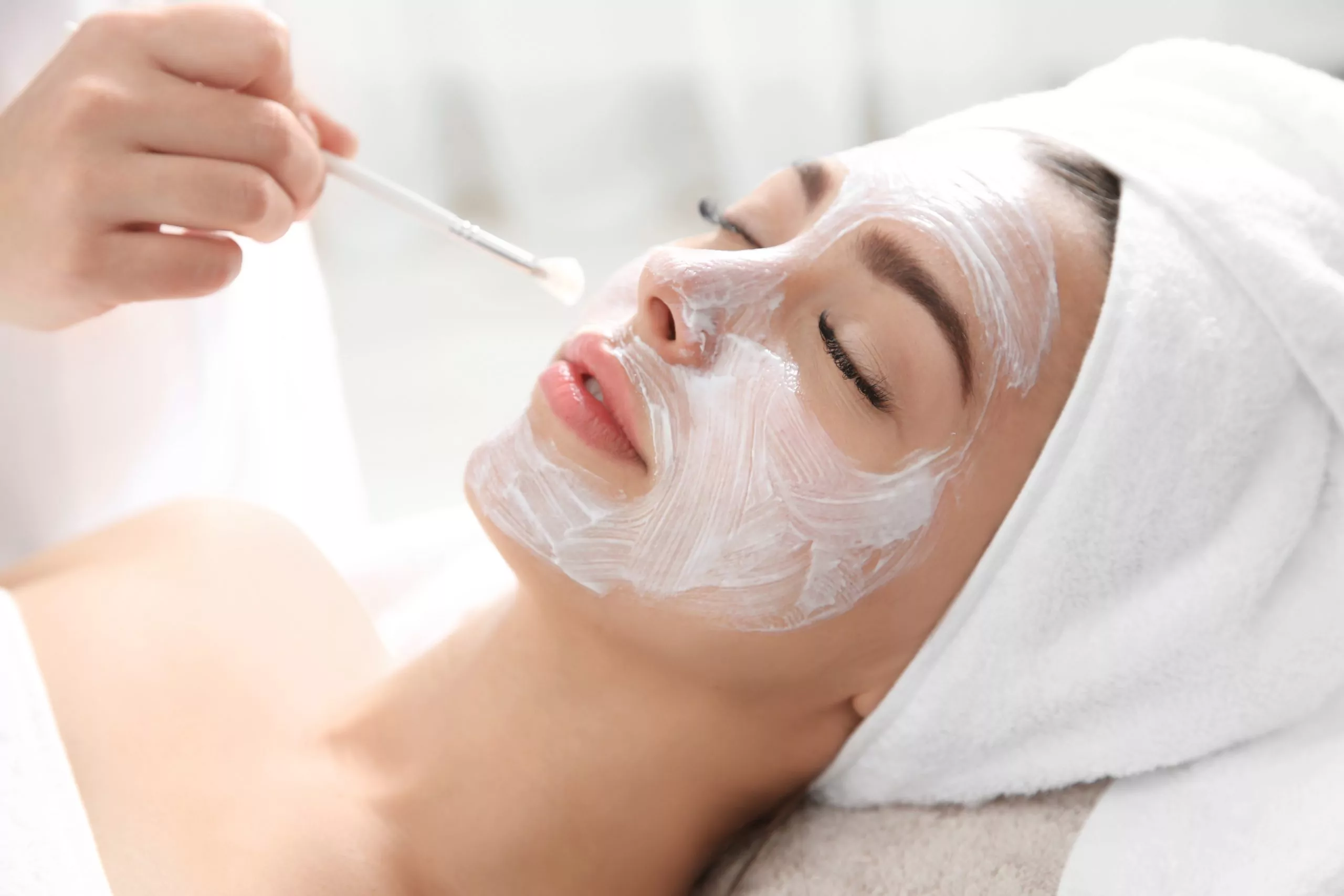 Thoa mặt nạ chăm sóc da lên khuôn mặt khách hàng.